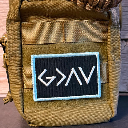 Close-up of a tactical pouch in olive drab green with a black rectangular embroidered patch featuring white stylized lettering and a light blue border.