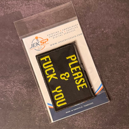 A black rectangular embroidered patch with yellow text reading 'PLEASE & FUCK YOU' inside a clear plastic sleeve, mounted on a branded white backing card. The backing card shows the JEKSP Professional logo and text including 'Printing | Embroidery | Engraving | Supplies | Digital Services' and 'Made in Nashville, Tennessee.