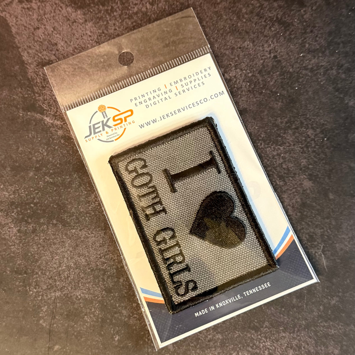 A packaged embroidered patch reading 'I <heart> GOTCHA GIRLS' on a dark textured background, mounted on a branded JESP transfer/embroidery card and photographed on a dark stone-like surface.