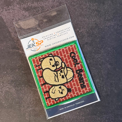 An embroidered patch in its clear plastic packaging, featuring three cartoonish beige heads on a red brick background with green borders and black text reading 'Call of Thieves'. The packaging header shows the JEKSP brand logo and contact details.