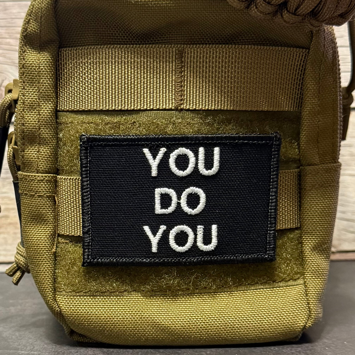 A tactical pouch in olive drab green nylon with a black rectangular patch on the front that reads 'YOU DO YOU' in white embroidered letters.