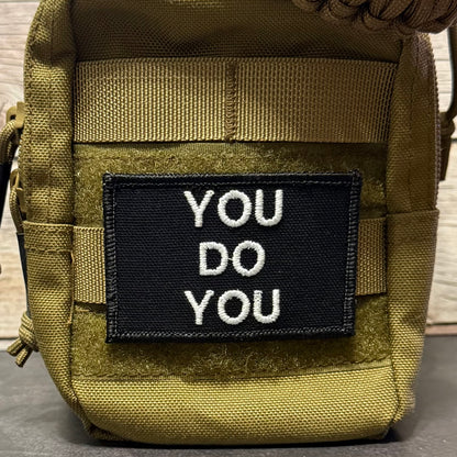 A tactical pouch in olive drab green nylon with a black rectangular patch on the front that reads 'YOU DO YOU' in white embroidered letters.