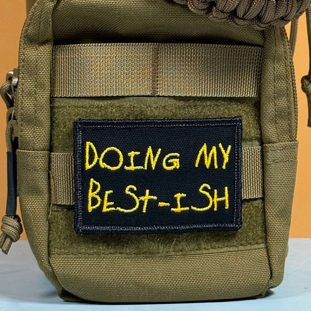 An olive green tactical pouch with a black embroidered patch featuring yellow text that reads 'DOING MY BEST-ISH'.