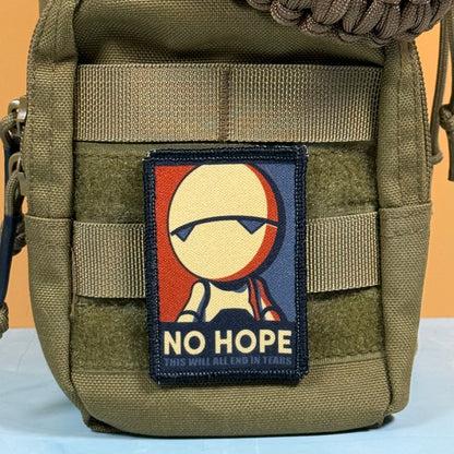 An olive drab tactical pouch with a rectangular embroidered patch featuring a stylized face and the text 'NO HOPE' and 'THIS WILL ALL END IN TEARS'.