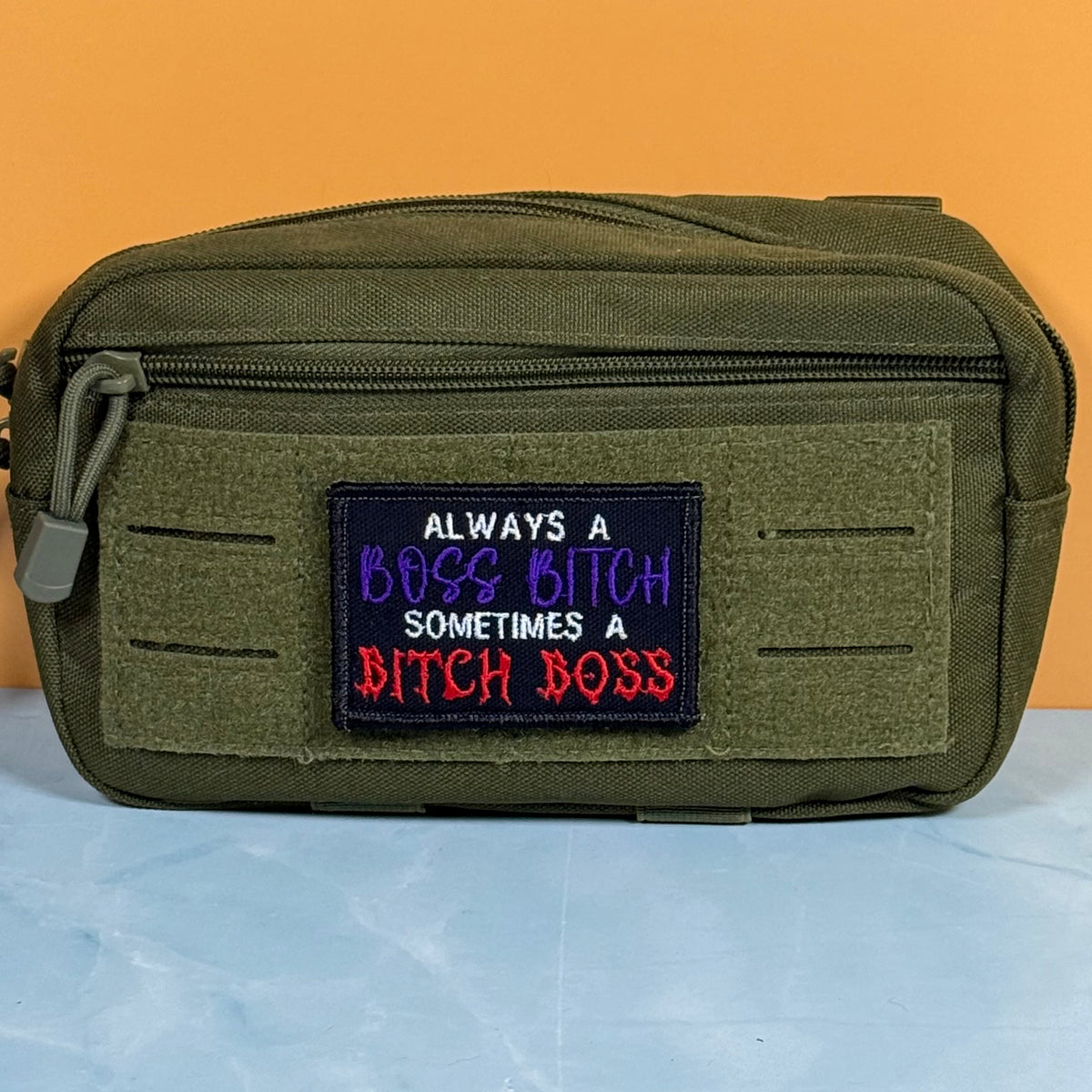 An olive green tactical pouch with a front hook-and-loop patch featuring the embroidered text 'ALWAYS A BOSS BITCH SOMETIMES A BITCH BOSS' in white, purple, and red.