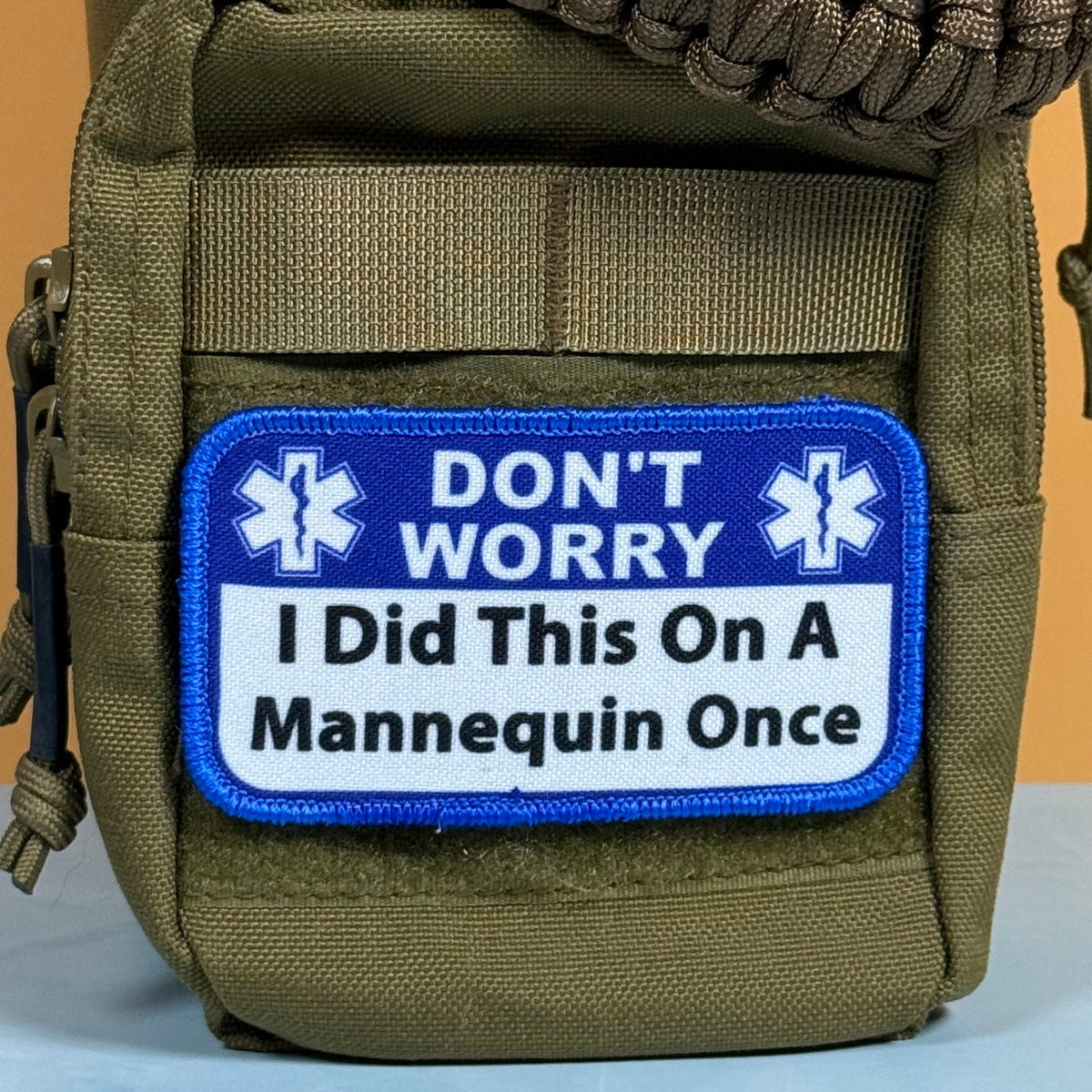 I Did This On a Mannequin Once printed canvas morale patch with the design letteringT WORRY I Did This On A Mannequin Once' in black lettering on a white background with a blue border, displayed on an olive green tactical pouch.
