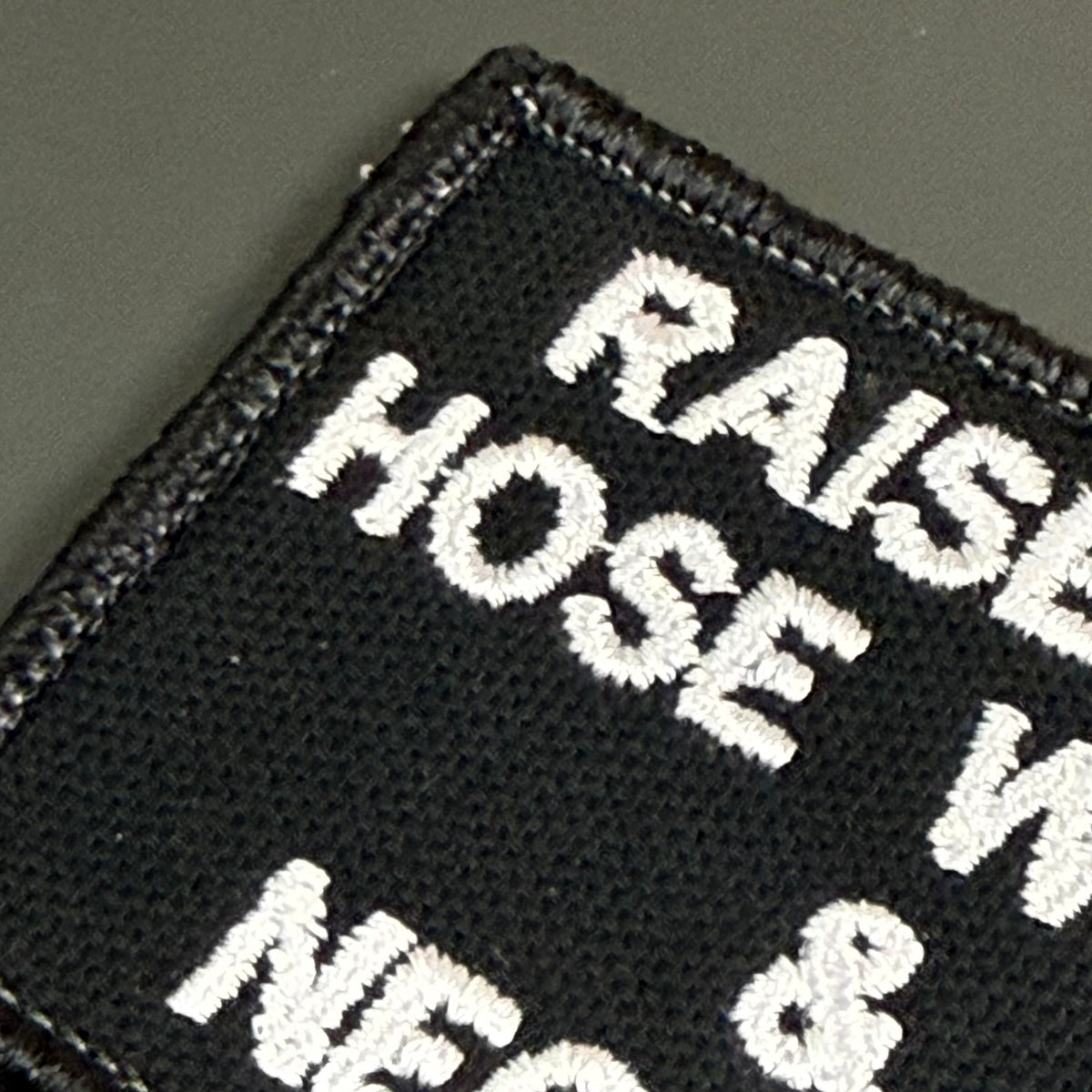 Raised on Hose Water & Neglect embroidered morale patch: black embroidered patch with white text reading 'RAISE HOSE W NEC &' on a dark gray background.