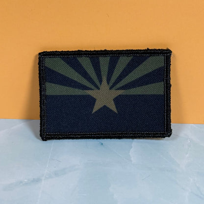 Arizona State Flag printed canvas morale patch featuring the Arizona state flag in a dark camouflage pattern, set against a split orange and light blue background.