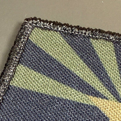 Arizona State Flag printed canvas morale patch, close-up of a woven fabric patch with a geometric sunburst pattern in olive green, dark navy, and tan, finished with a dark stitched border.