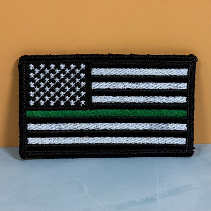 Thin Green Line Tactical American Flag embroidered morale patch: of a black and white American flag with a single green stripe, representing a 'Thin Green Line' design, displayed against a solid orange background.