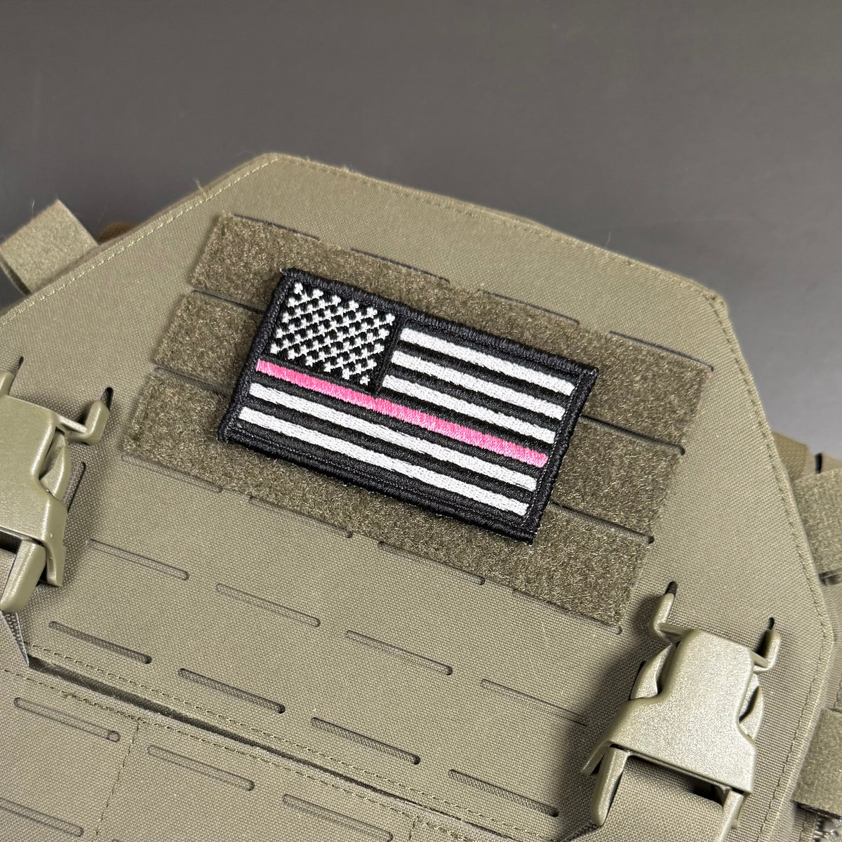 Breast Cancer Awareness Thin Pink Line American Flag embroidered morale patch: embroidered American flag patch with a single pink stripe, displayed on a tan tactical vest with MOLLE webbing and quick-release buckles.