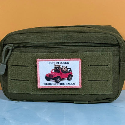 Get In Loser We're Getting Tacos printed canvas morale patch, an olive green canvas pouch with a front zipper and a rectangular patch featuring a red jeep with two dogs and the design letteringRE GETTING TACOS'.
