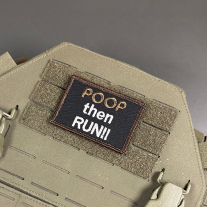 A tactical embroidered patch reading 'POOP then RUN!!' in white and gold thread on a black background, attached to tan webbing on a coyote brown tactical vest or plate carrier.