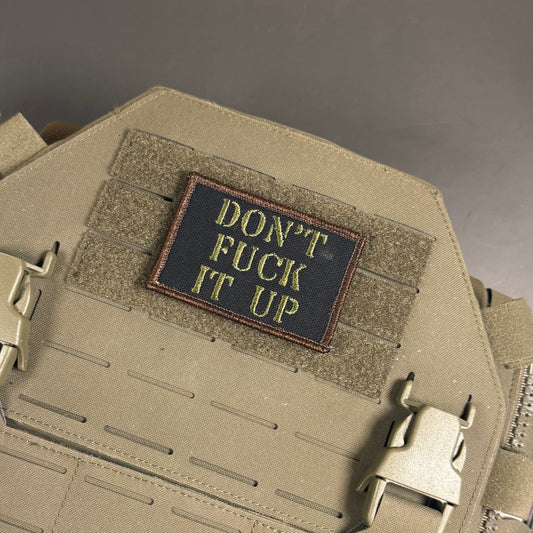 Don't Fuck It Up embroidered morale patch: with the text 'DON'T FUCK IT UP' in yellow on a black background, sewn onto a tan tactical vest with Velcro and quick-release buckles.