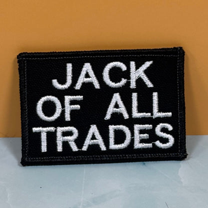 Jack Of All Trades embroidered morale patch: black embroidered patch with white text reading 'JACK OF ALL TRADES' on a two-tone background.