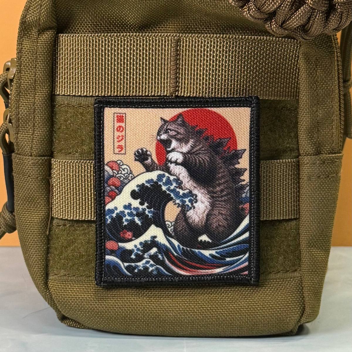Catzilla printed canvas morale patch, an olive green tactical pouch featuring a rectangular printed patch with a Japanese-style cat wave artwork, shown against a plain background.