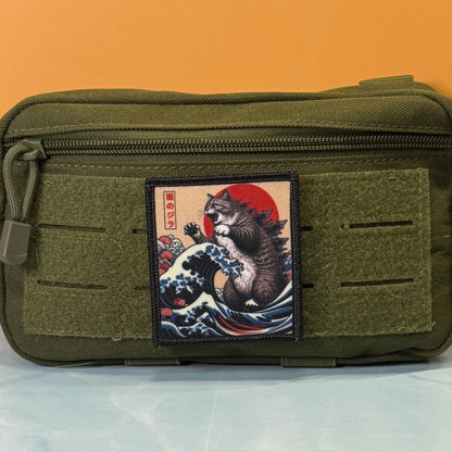 Catzilla printed canvas morale patch, an olive green tactical pouch featuring a rectangular printed patch with a Japanese ukiyo-e style cat riding a wave under a red sun.