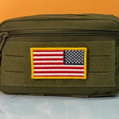 American Flag embroidered morale patch: olive green tactical pouch with a rectangular embroidered American flag patch on the front, set against a solid orange background.