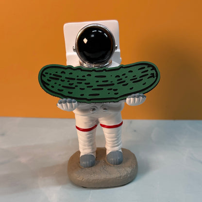 Dill Pickle laser-engraved synthetic morale patch: a novelty figurine of an astronaut holding a large green pickle, standing on a gray base against an orange background.