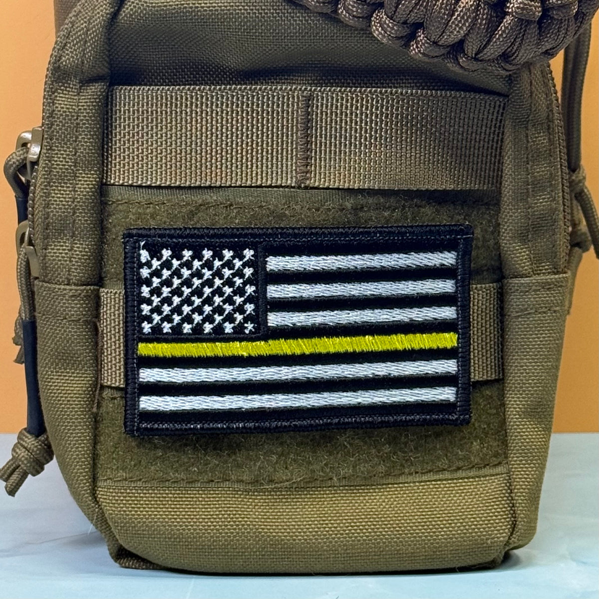 Thin Yellow Line American Flag embroidered morale patch: pouch in olive drab nylon featuring an embroidered 'Thin Blue Line' American flag patch on the front pocket.