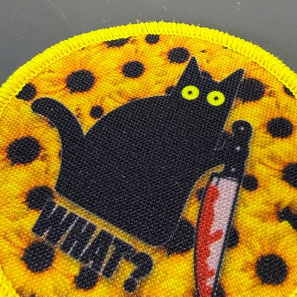 Murder Cat and Sunflowers printed canvas morale patch, a close-up of a circular printed patch featuring a black cat holding a bloody knife, with the design lettering in black text on a yellow background with black spots.