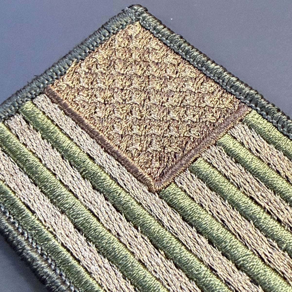 Subdued FDE Tactical American Flag embroidered morale patch: embroidered military rank patch featuring diagonal stripes in olive green and tan, with a textured gold diamond at the top and a dark green border.
