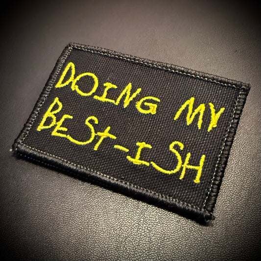 A rectangular black embroidered patch with yellow text reading 'DOING MY BEST-ISH' on a dark textured surface.