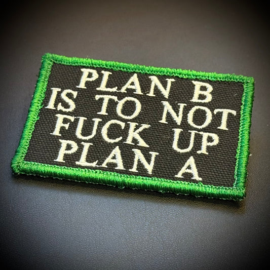 A rectangular embroidered patch with a black background and bright green border, featuring the text 'PLAN B IS TO NOT FUCK UP PLAN A' in white capital letters, shown on a dark gray surface.