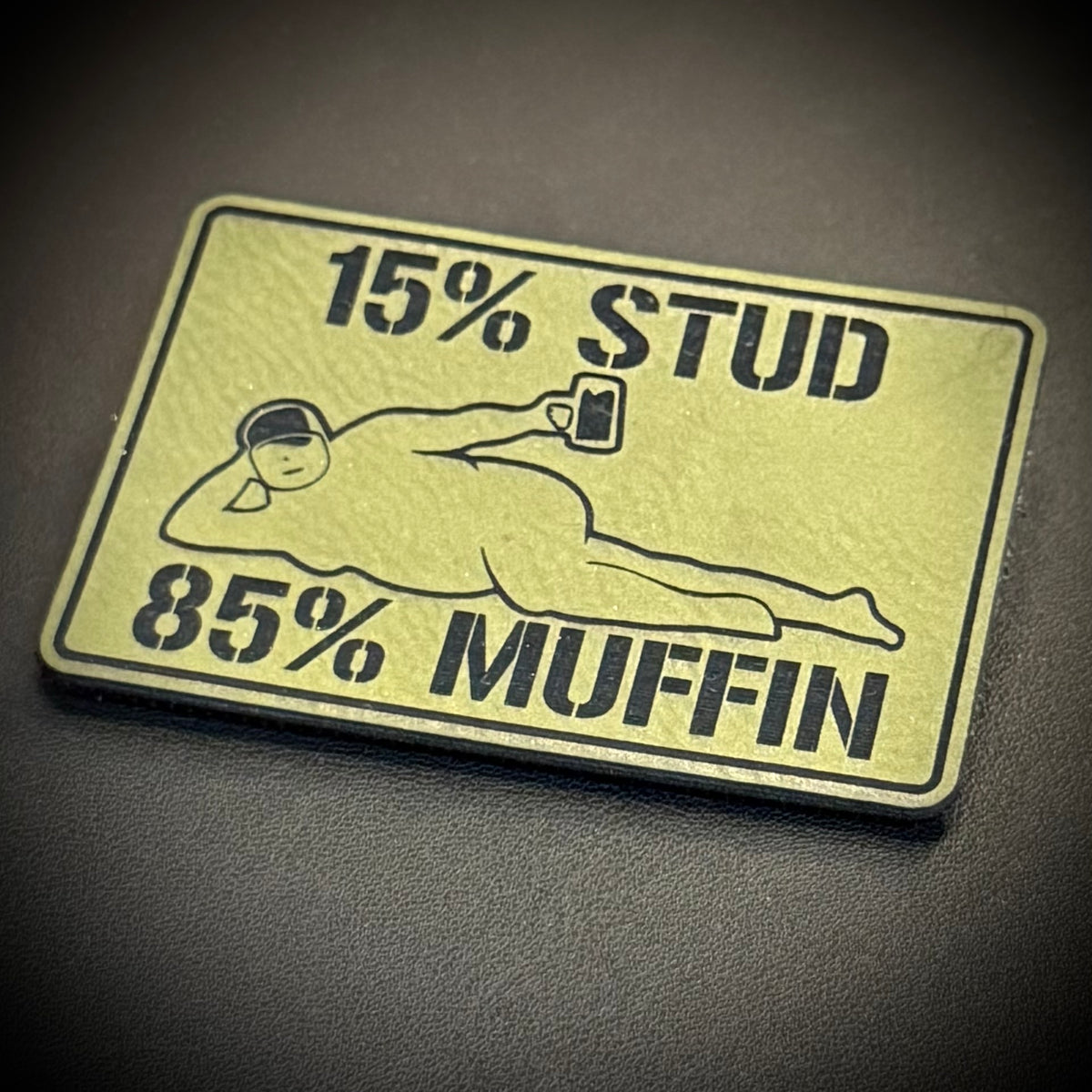 15% Stud 85% Muffin Funny Dad Bod laser-engraved synthetic morale patch: a rectangular novelty patch with rounded corners featuring a black graphic and text on a pale yellow background. The text reads '15% STUD' at the top and '85%.