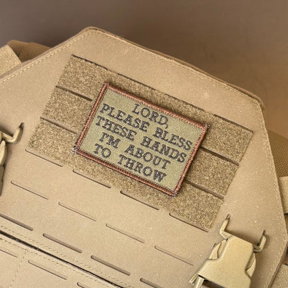 Lord, Bless These Hands I'm About To Throw embroidered morale patch: beige tactical bag with a rectangular embroidered patch reading 'LORD, PLEASE BLESS THESE HANDS I'M ABOUT TO THROW' on a tan webbing panel.