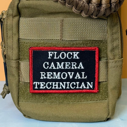 Flock Camera Removal Technician embroidered morale patch: olive green tactical pouch with a black embroidered patch that reads 'FLOCK CAMERA REMOVAL TECHNICIAN' in white text with a red border.