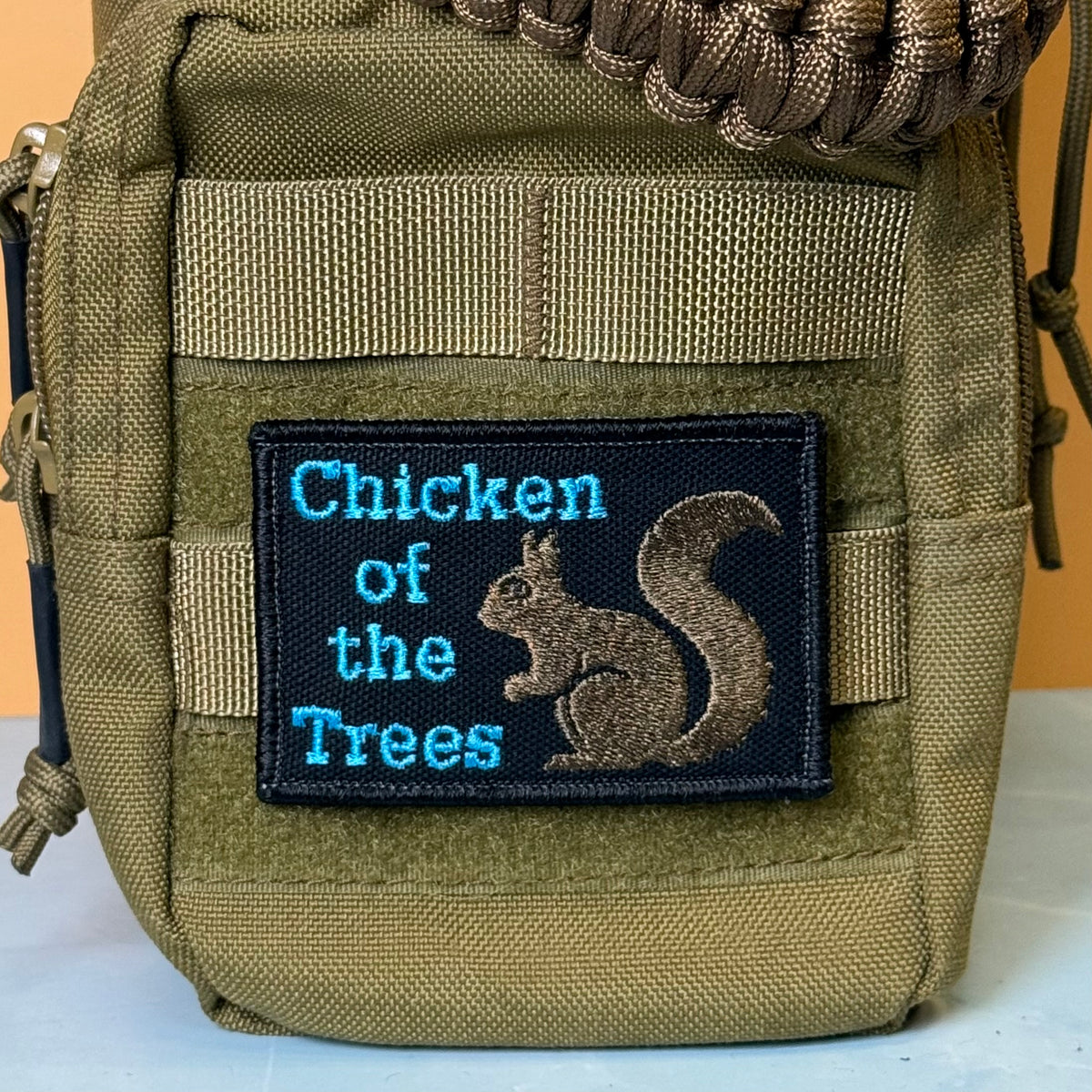 Squirrel, Chicken of the Trees embroidered morale patch: olive green tactical pouch featuring a black embroidered patch with the text 'Chicken of the Trees' in blue and a brown squirrel illustration.