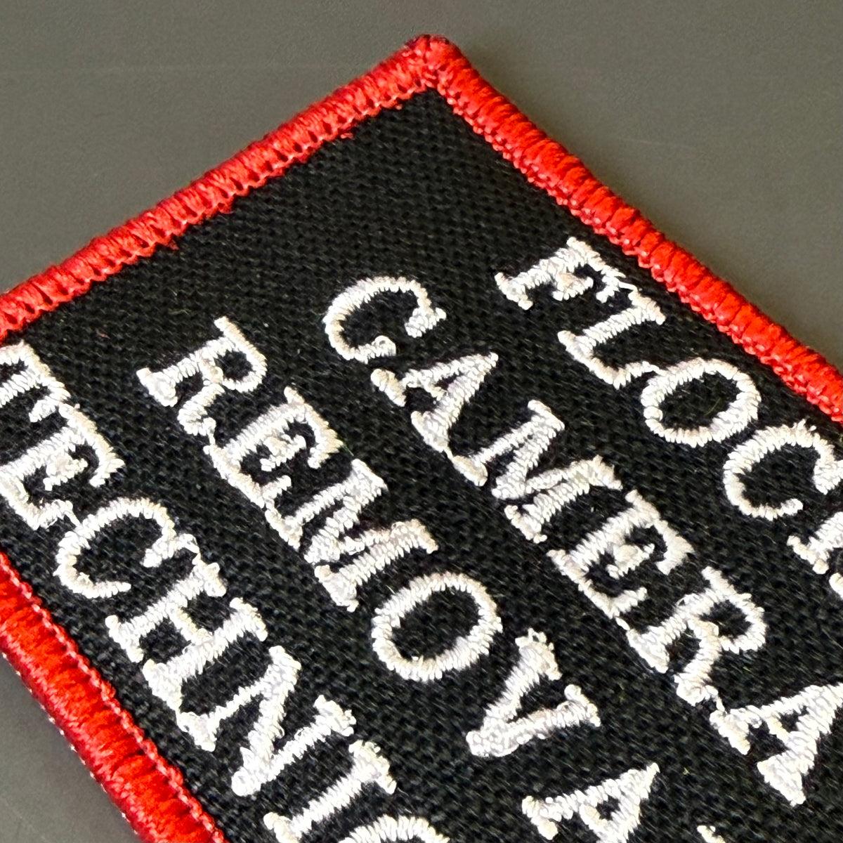 Flock Camera Removal Technician embroidered morale patch: rectangular embroidered patch with a black background, red stitched border, and white text reading 'FLOCC.