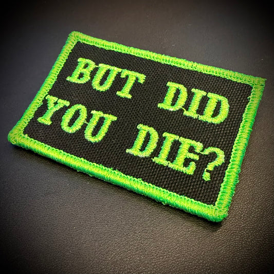 A rectangular embroidered patch with a black background and bright neon green border and text reading 'BUT DID YOU DIE?' on a dark textured surface.