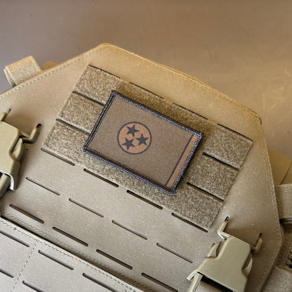 Tennessee State Flag printed canvas morale patch, a rectangular tan tactical patch featuring the Tennessee state flag design with three stars, mounted on a tan MOLLE webbing strap of a tactical vest or backpack.