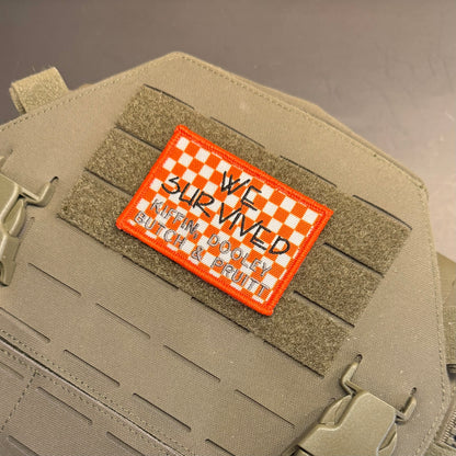 We Survived, Tennessee Football embroidered morale patch: tactical patch with an orange border and a white-and-orange checkered top, reading 'WE SURVIVED KAREN DOOLEY' in black script, shown attached to tan webbing on a matching.