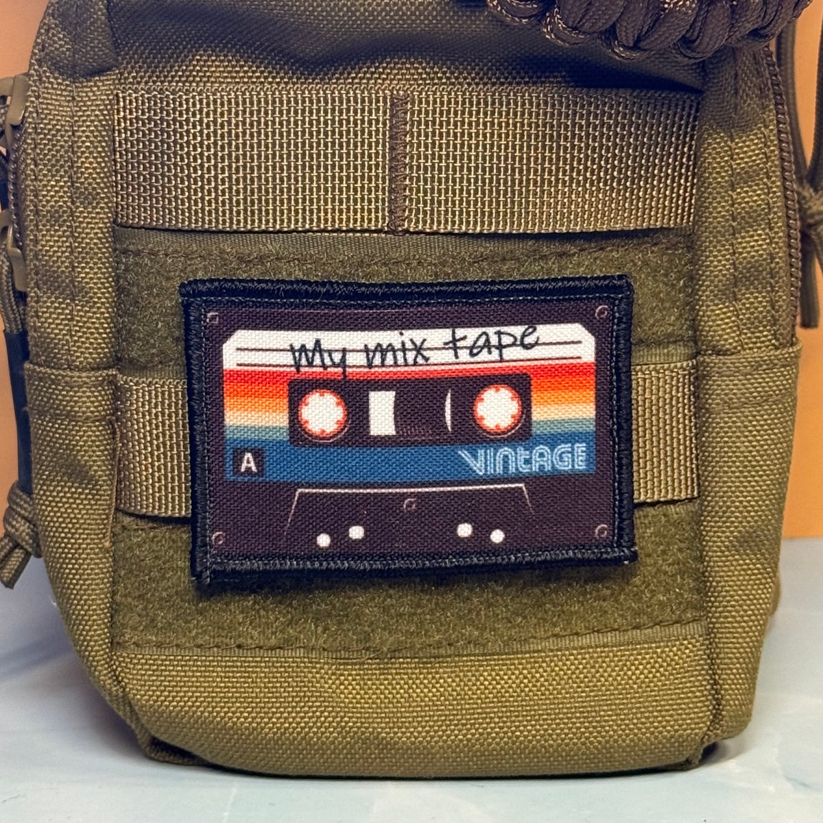 An olive green tactical pouch featuring a rectangular patch with a retro cassette tape design and the text 'My mix tape VINTAGE'.