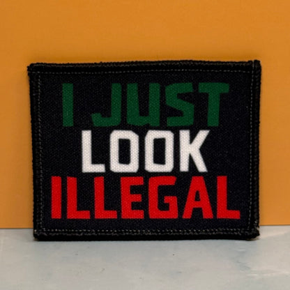 I Just Look Illegal printed canvas morale patch, design lettering in green, white, and red lettering, shown against an orange background.
