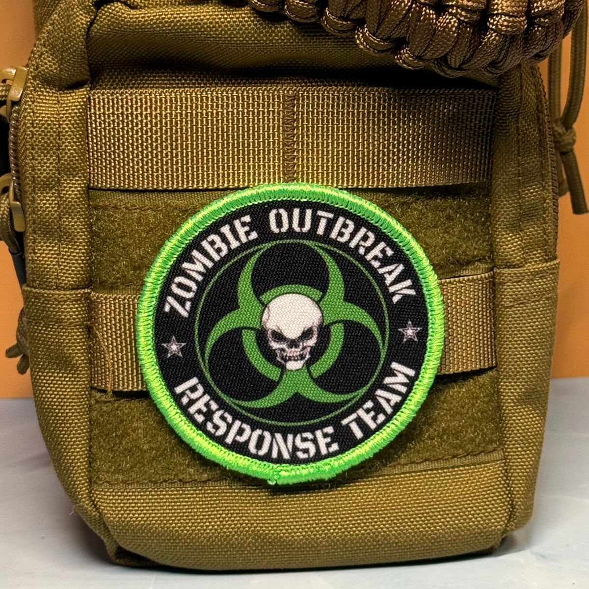Zombie Outbreak Response Team printed canvas morale patch, the design lettering with a skull and biohazard symbol, attached to an olive drab MOLLE pouch.
