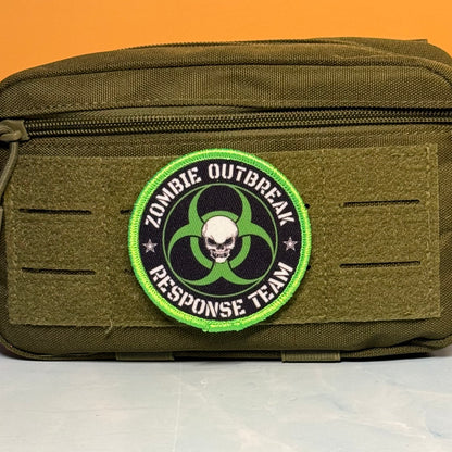 Zombie Outbreak Response Team printed canvas morale patch, an olive green tactical pouch with a circular printed patch the design lettering featuring a skull and biohazard symbol, set against an orange background.