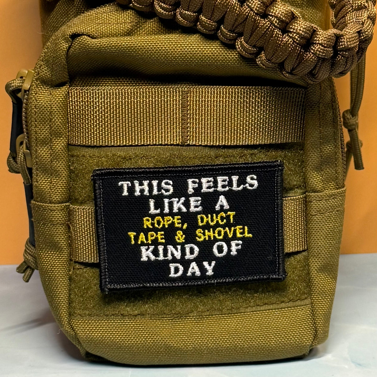 This Feels Like A Rope & Duct Tape Kind Of Day embroidered morale patch: olive green tactical pouch with a black embroidered patch that reads 'THIS FEELS LIKE A ROPE, DUCT TAPE & SHOVEL KIND OF DAY' in white and yellow text. A.