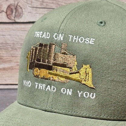Green cap with embroidered design and text on a wooden surface