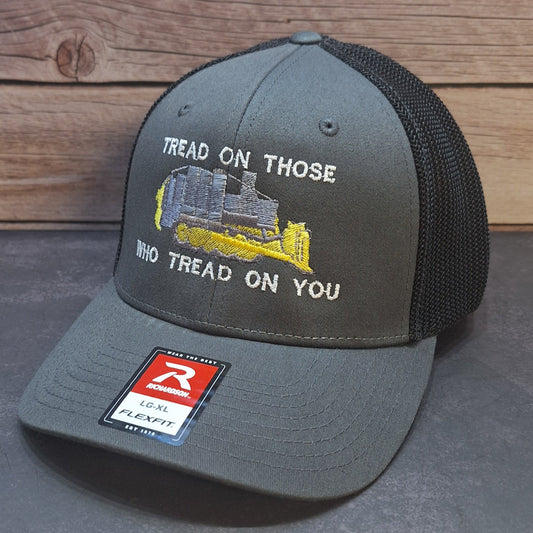 Gray cap with embroidered design and text on a wooden surface