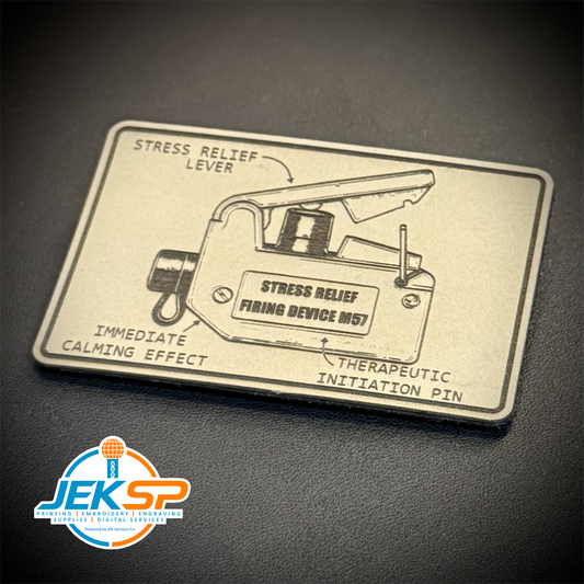 A rectangular silver-toned metal plaque featuring an engraved diagram of a stress relief device with labeled callouts, photographed on a dark textured surface. A circular 'JEKSP' watermark appears in the lower-left corner.