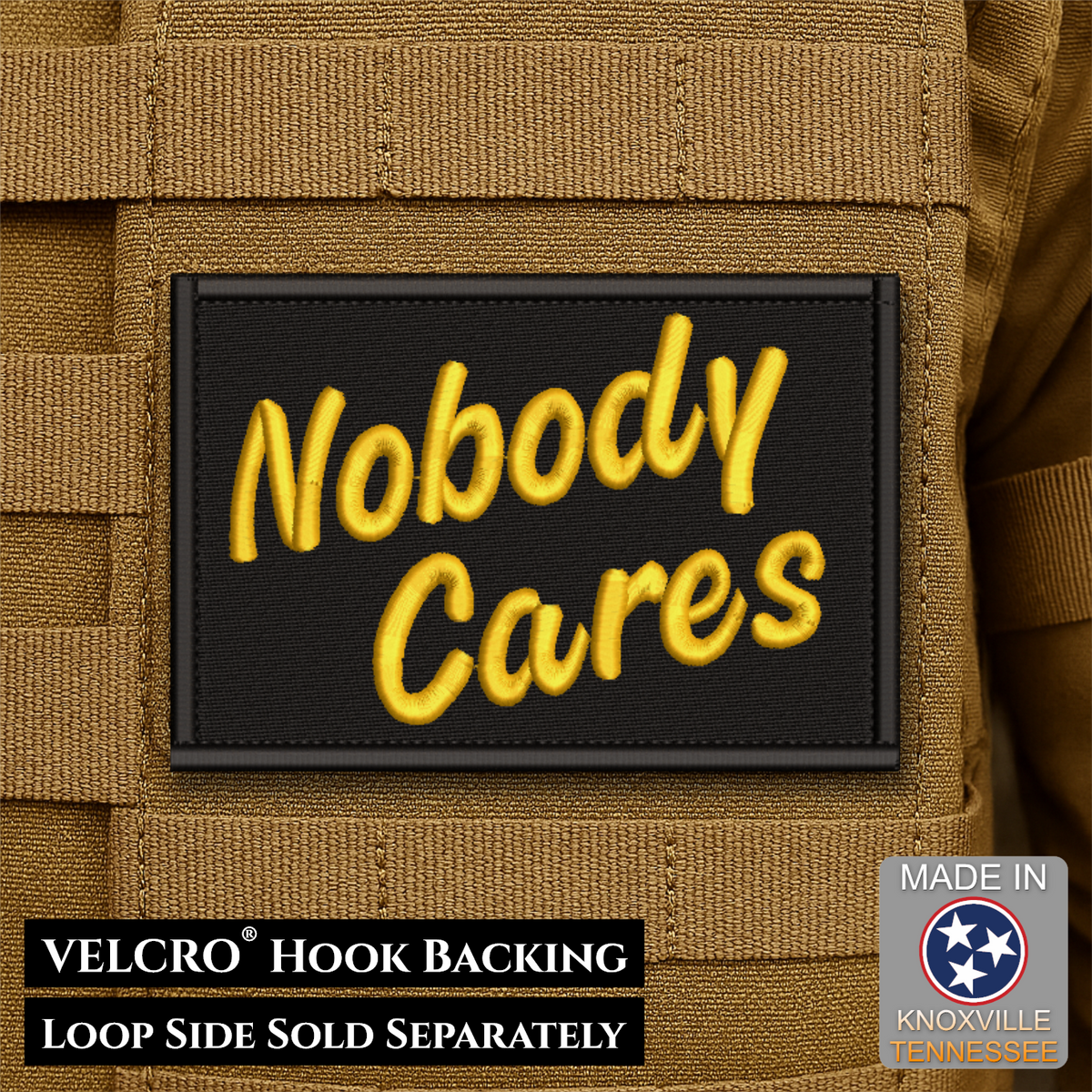 A rectangular black patch with raised yellow embroidered text reading 'Nobody Cares' attached to tan tactical webbing. Text at the bottom states 'VELCRO HOOK BACKING LOOP SIDE SOLD SEPARATELY,' and a 'Made in Knoxville Tennessee' badge appears in the lower right.