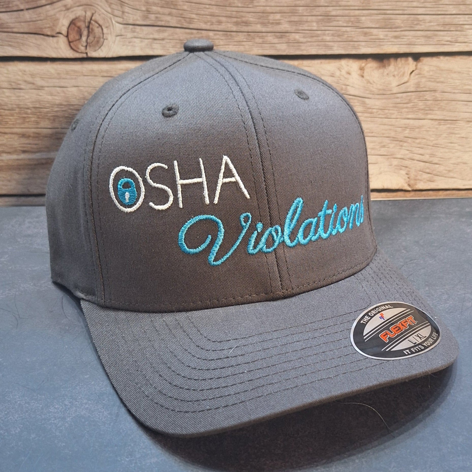 Gray cap with 'OSHA Violation' text on a wooden surface