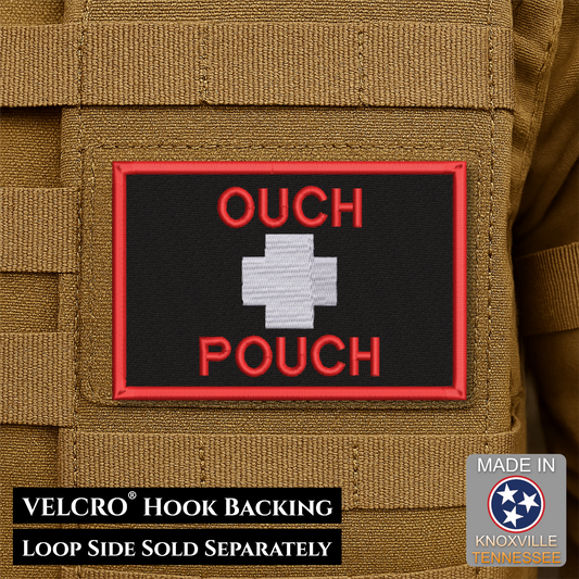 A rectangular embroidered patch with a black background, red border, red text reading 'OUCH POUCH,' and a white cross symbol in the center, shown attached to tan tactical fabric. Text at the bottom notes VELCRO hook backing and loop side sold separately; a 'Made in Knoxville Tennessee' badge appears in the lower right.