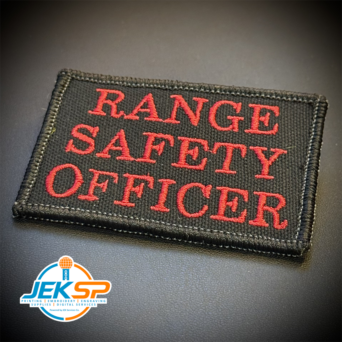 Range Safety Officer Patches & ID Plates – 2x3 Patch or 3x8 ID Panel – Tactical Gear embroidered or reflective range ID patch: black embroidered patch with the words 'RANGE SAFETY OFFICER' in red lettering, shown on a dark gray background. A.
