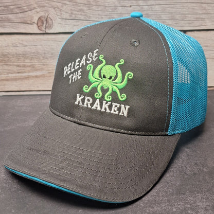 Gray and blue cap with 'Release the Kraken' text and octopus graphic on a wooden surface.