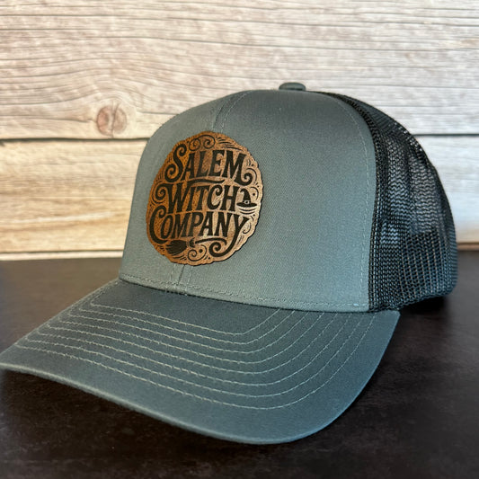 Gray cap with 'Salem Witch Company' logo on a wooden surface